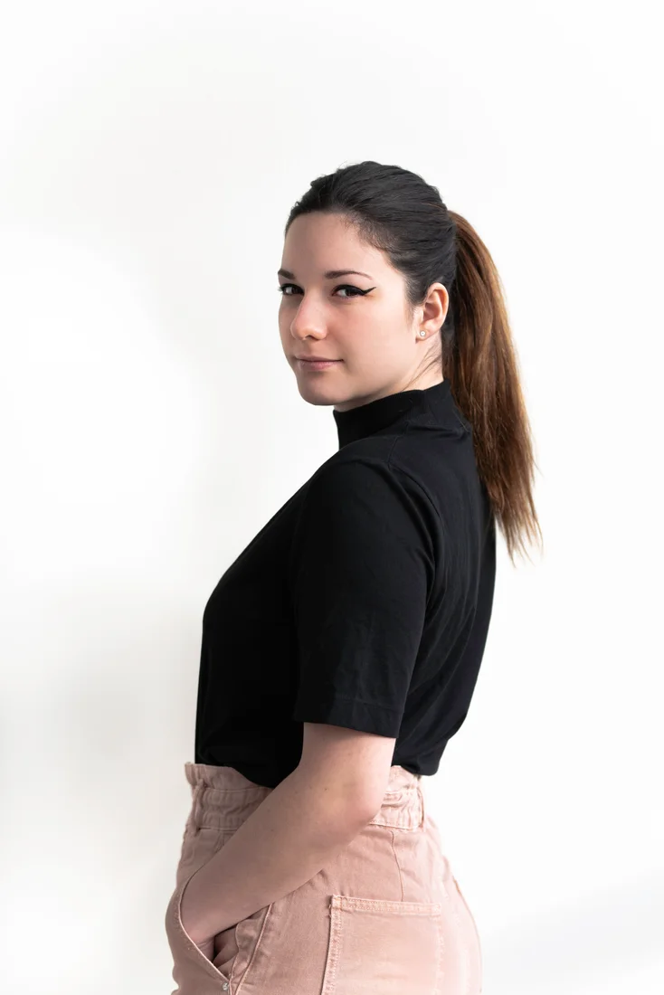 Portrait en couleur d’une femme de trois quarts sur fond clair.