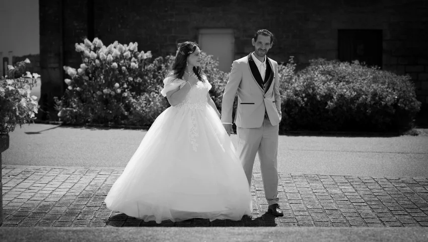Le couple devant une façade de pierre, photographié en noir et blanc.