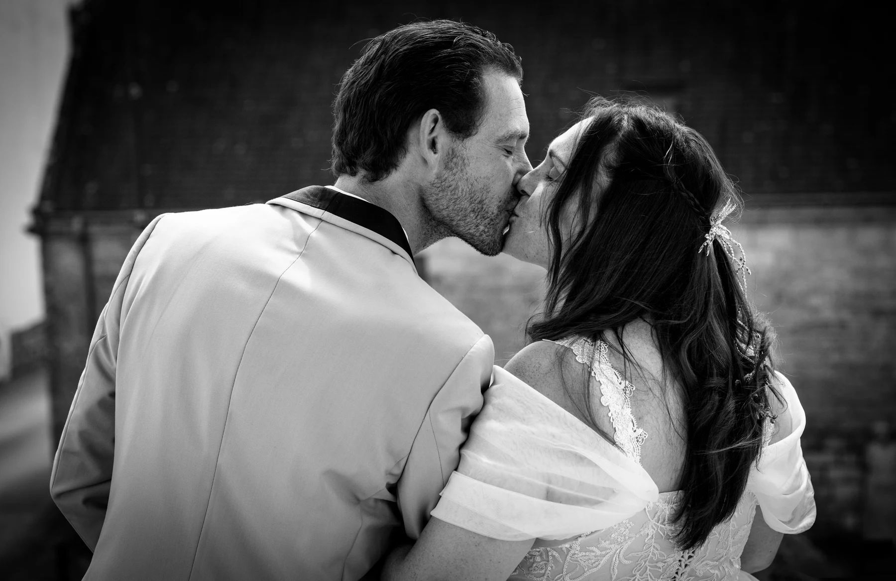 Les mariés s’embrassent, photographiés en noir et blanc.